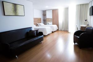 a hotel room with two beds and a couch at Victory Suites in Juiz de Fora
