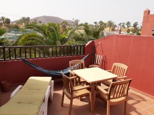 a table and chairs on a balcony with a hammock at Oasis Waves House in Corralejo