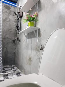 La salle de bains est pourvue de toilettes avec une plante sur une étagère. dans l'établissement Baan Thabthong Homestay (บ้านทับทอง โฮมสเตย์), à Ban Pak Nam