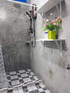 a bathroom with a shower with a plant on a shelf at Baan Thabthong Homestay (บ้านทับทอง โฮมสเตย์) in Ban Pak Nam