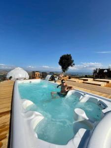 a man is sitting in a swimming pool at Barichara Glamping Valley in Barichara