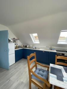 een keuken met blauwe kasten en een tafel met een stoel bij Blue Pearl Apartment in Downings