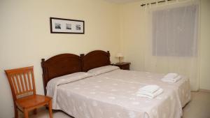 een slaapkamer met een bed met witte lakens en een stoel bij Apartamento Heliconia 3 in Valle Gran Rey