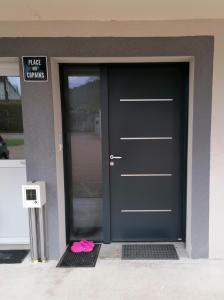 Eine schwarze Tür mit einem rosa Stück Papier daneben. in der Unterkunft Chambre et table d'hôtes La Meule in Poligny