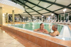 un hombre y una mujer sentados en una piscina en Hotel HegiQ - Adults Only Hotel, en Hegykő