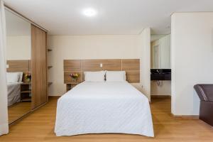 a bedroom with a large white bed and a mirror at Victory Suites in Juiz de Fora
