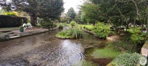 un flusso d’acqua con una persona seduta a un tavolo di AU FIL DE L'EAU a Milly-sur-Thérain