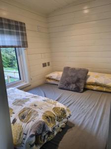 two beds in a room with a window at Glamping Hut - Riverview 5 in Garthbeibio