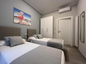 a bedroom with two beds and a painting of a woman on a beach at Adelasia al Corso in Alassio