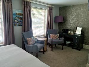 a bedroom with a bed and two chairs and a desk at The Ollerod in Beaminster
