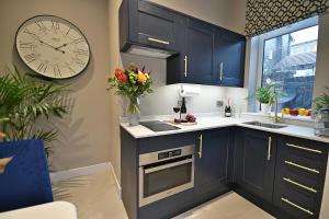 a kitchen with blue cabinets and a clock on the wall at Moat House in Rawtenstall