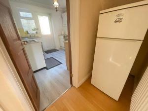 a kitchen with a white refrigerator in a room at Two Double Bedroom Maisonette with rear garden. 