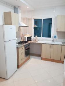 a kitchen with a white refrigerator and a microwave at Superb & Modern apartment at Berges Lac 2 close to Tunisia Mall in Tunis