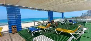 een balkon met stoelen en tafels en uitzicht op het strand bij מלון דירות על הים בת ים 39 in Bat Yam