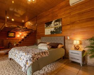 - une chambre avec un lit dans une pièce dotée de murs en bois dans l'établissement Bungalows Las Iguanas Arenal Volcano, à Fortuna