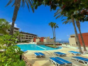 Una piscina con tumbonas azules y palmeras. en Playa Paraiso, en Playa Paraiso