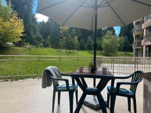 a table with two chairs and an umbrella on a patio at Flora Hotel Apartment 103 in Borovets