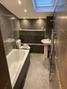 a bathroom with a bath tub and a sink at Sands Reach, dog friendly Tenby house in Tenby