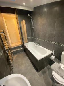 a bathroom with a tub and a toilet and a sink at Sands Reach, dog friendly Tenby house in Tenby