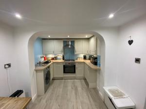 a kitchen with white cabinets and a sink and a dishwasher at Sands Reach, dog friendly Tenby house in Tenby