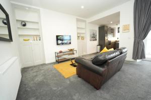 a living room with a leather couch and a table at Immaculate 1-Bed Apartment in Merthyr Tydfil in Merthyr Tydfil