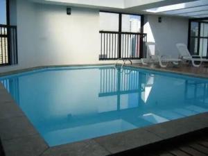 a large swimming pool with blue water in a building at Bienal First Class Flat Service in São Paulo