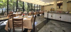 a dining room with tables and chairs and windows at Bienal First Class Flat Service in São Paulo