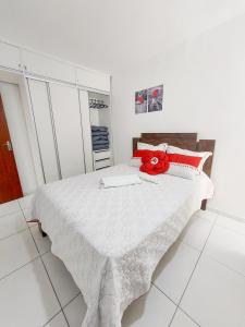 Un dormitorio blanco con una cama con una flor roja. en Prainha Paradise, en Arraial do Cabo
