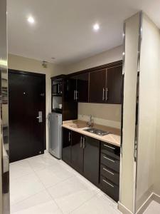 a kitchen with black cabinets and a stainless steel refrigerator at Al Muhaidb Al Taif Hotel in Al Hada