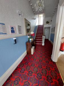 a hallway with a staircase and a red carpet at The Patricia in Torquay