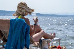 a woman sitting on a beach with a glass of wine at Yasos By The Sea in Çeşme
