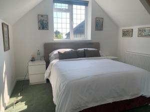a bedroom with a large white bed and a window at La Mer in Ferring
