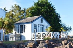 une maison blanche avec une clôture et des arbres dans l'établissement The West Usk Lighthouse Lightkeepers Lodge, à Newport