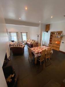 a living room with a table and a couch at Tranquil 2 Bedroom Cottage With Hot Tub Sea View Teach Cha in Sessiagh