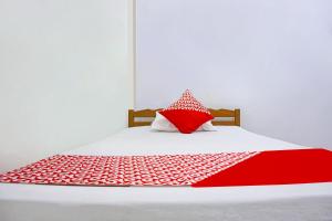 ein rotes und weißes Bett mit einem roten Kissen darauf in der Unterkunft SPOT ON 91786 Kilana Homestay in Makassar