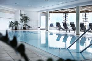 una piscina con sedie in un edificio di Hotel Birkenhöhe a Hirschegg