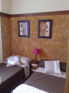 een slaapkamer met twee bedden en twee foto's aan de muur bij Candelario in Candelario