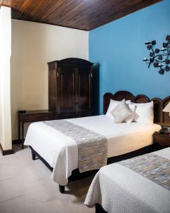 a bedroom with two beds and a blue wall at Hotel Plaza Copan in Copan Ruinas