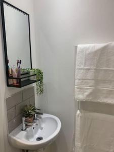 La salle de bains est pourvue d'un lavabo blanc et d'un miroir. dans l'établissement Alto - Lovely 2 Bedroom Serviced Apartment Bristol by Mint Stays, à Bristol