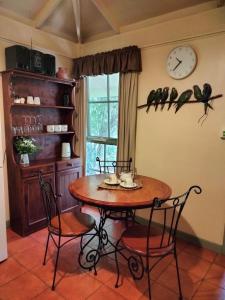 a dining room table with two chairs and a clock on the wall at Kalimna Woods Cottages in Lakes Entrance