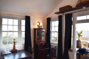 Cette chambre dispose de fenêtres, d'une table et d'une armoire en bois. dans l'établissement The West Usk Lighthouse Lightkeepers Lodge, à Newport