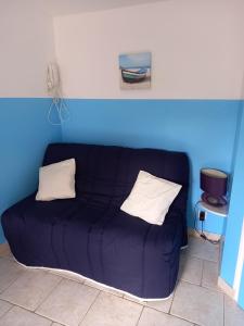een bank in een kamer met een blauwe muur bij GITE ENTRE TERRE ET MER in Mareuil-sur-Lay