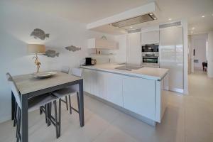 a white kitchen with a table and a counter at Appartements Croisette Grand Hôtel in Cannes
