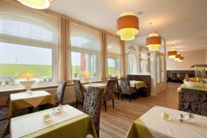 a dining room with tables and chairs and windows at Strandvilla an der Kaiserwiese in Norderney