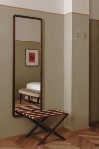 a mirror on a wall with a bench in a room at Parkhotel Mondschein, a Member of Design Hotels in Bolzano