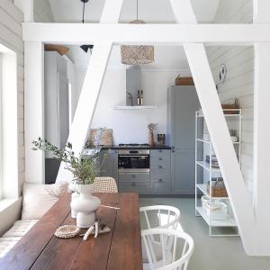 cocina con mesa de madera y sillas blancas en Casa Pueblo Viejo, en Ouddorp