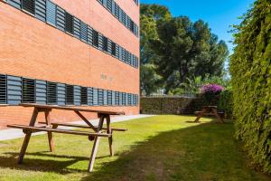twee picknicktafels voor een bakstenen gebouw bij Micampus Estanislao del Campo, Student Residence in Sevilla