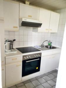 a kitchen with white cabinets and a stove and a sink at Ferienwohnung Daliah in Wangels