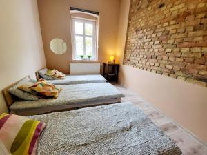- 2 lits dans une chambre avec un mur en briques dans l'établissement Tanie spanie przy Targach Poznańskich - zameldowanie bezobsługowe-, à Poznań