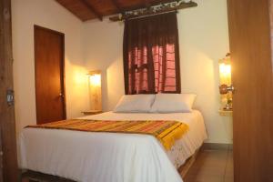 a bedroom with a white bed with a window at Finca la Mariposa, Santa Elena in Santa Elena